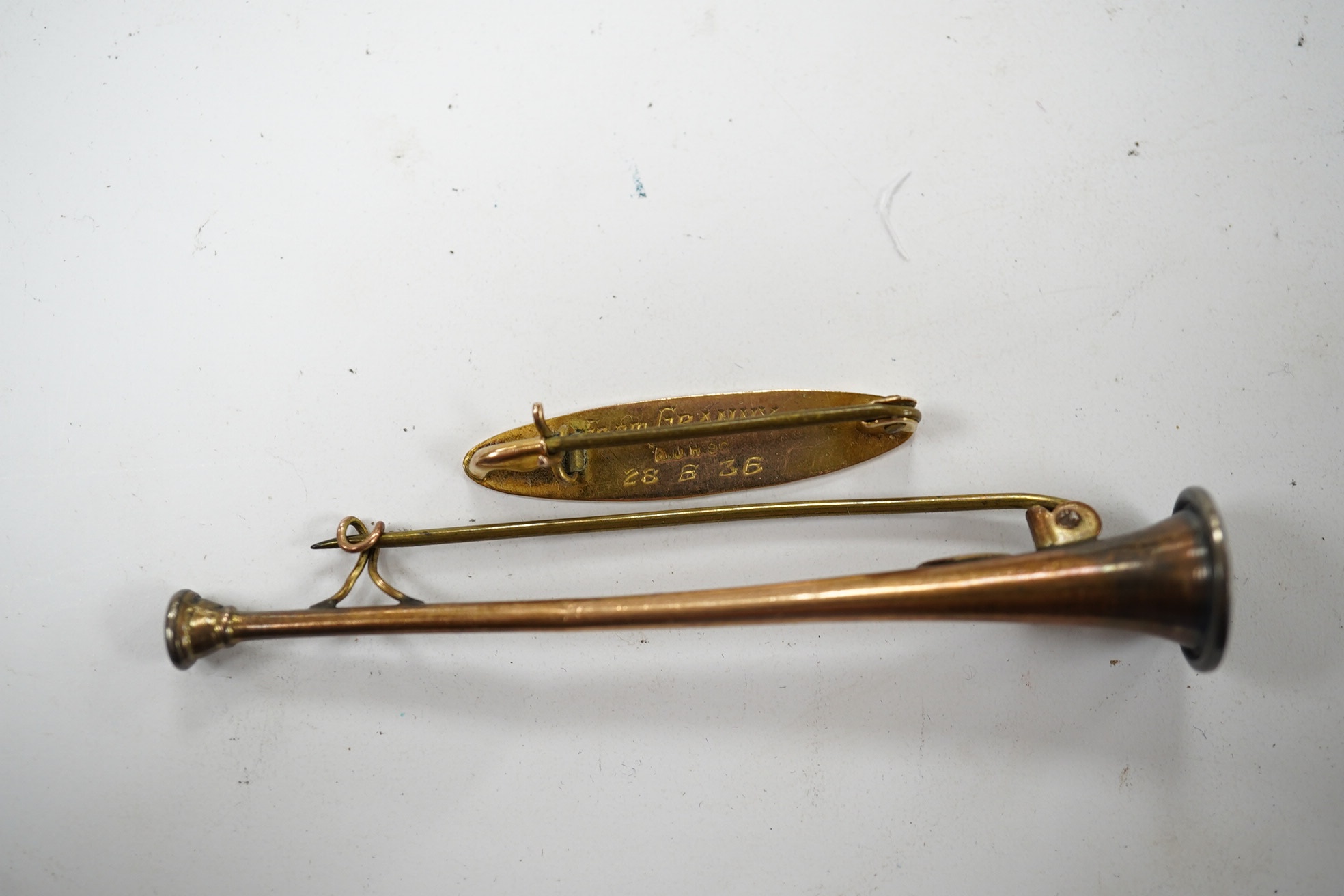 A '9ct and silver' hunting horn bar brooch, 62mm, together with a 1930's yellow metal brooch, with engraved inscription. Condition - fair